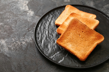 Plate with toasted bread on grunge background