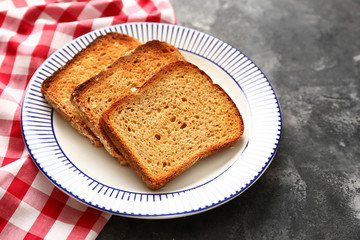 Plate with tasty toasted bread on grunge background