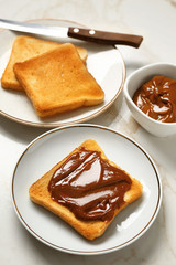 Tasty toasted bread with chocolate spreading on table