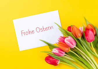 colorful tulips on a yellow background and german text frohe ostern, in english happy easter