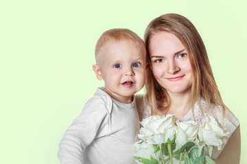 Happy mothers day. Mom with son are holding flowers white roses. Family portrait on a light green background with space for inscription