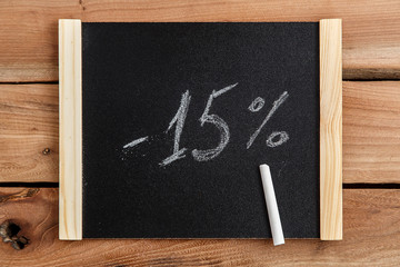 Black Board in wooden frame on wooden background with inscription minus fifteen percent