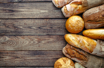 Assortment of baked bread on wooden table background,top view