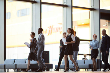 Full length portrait of business people walking across office hall of lobby, copy space