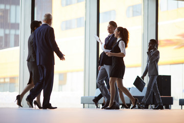 Group of business people walking across office hall of lobby, copy space