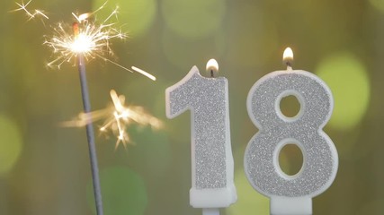 Number 18 birthday celebration candle against a bright lights and golden bokeh background. eighteenth birthday - Powered by Adobe