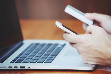 Fototapeta premium close up people hands holding credit card and using phone and computer laptop. Online shopping purchase Sell or Payment.