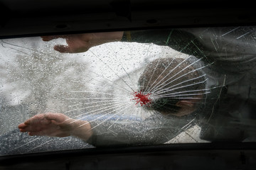 Pedestrian hit by a car, with blood on the splintered windshield