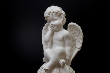Beautiful white angel on black background close-up. Symbol of love, faith and hope