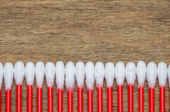 White cotton ear sticks of red color on a wooden background macro