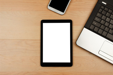 Tablet and smartphone with blank screen and laptop on wooden desk
