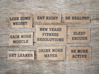 New Year Fitness Resolutions concept - New Year’s Fitness Resolutions and list written on papers and arranged on wooden table.
