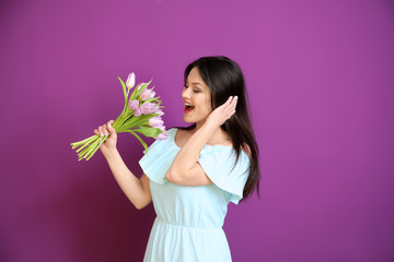 Young woman with bouquet of flowers on color background. 8 March celebration