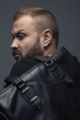 Forever Black concept. Attractive handsome man in trendy casual clothing with leather bag over gray background. Close up. Studio shot