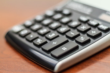 Math calculator number pad keys isolated on a dark wood table with blurred background