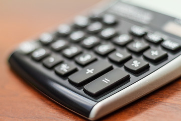 Math calculator number pad keys isolated on a dark wood table with blurred background
