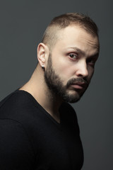 Fototapeta premium Male beauty concept. Fabulous at any age. Portrait of 35-year-old man standing over dark gray background. Modern haircut. Rocker, biker style. Close up. Studio shot