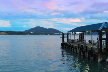 Fishing sea pier in a beautiful turquoise sea at sunset on the background of small islands, Malaysia, the island, the Strait of Malacca, the concept of vacation, travel.