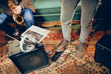 Musicians having rehearsal in home studio. On the floor amplifiers, laptop and headphones.