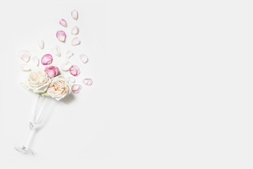 Wedding , birthday, Valentines day party composition. Champagne glass with pink rose flowers and petals isolated on white table background. Celebration, love concept. Flat lay, top view. Empty space.