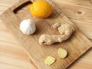 Fresh ginger fruit lies on a light wooden background next to lemon and garlic, health concept