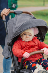 Obraz premium The little baby is sitting in the pram.