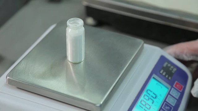 Pharmacist puts vial with powder on the scales and weighs