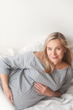 Happy pregnant woman lie on a bed at home