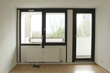 Broom stands on the floor against the wall in the middle of an empty bright room