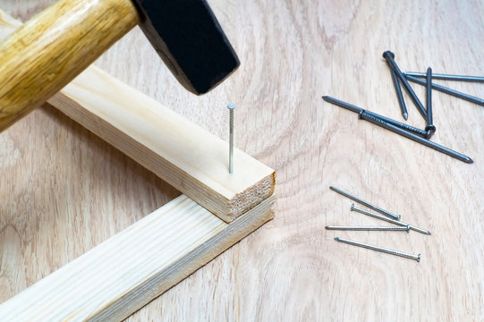 Hammer hammers a nail into a wooden block.