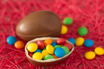 Easter. Chocolate eggs with multicolored candies lie on a pink background.