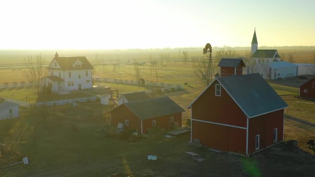 A drone aerial at dawn establishing shot over a classic farmhouse farm and barns in rural midwest America, York, Nebraska.