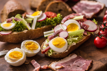 Baguette sandwich fresh vegetable dressing bacon panchetta tomatoes eggs and onion. Healthy nutrition breakfast or appetizer