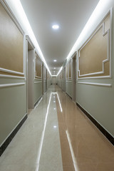 Vanishing perspective of a long indoor corridor with doors and reflective lights.