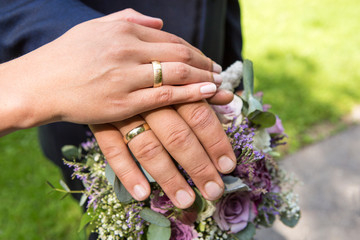 Fototapeta premium Hands of bride and groom with flower bouquet