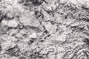 Closeup of rough river water surface with water splashes in black and white. Abstract river, sea and ocean texture. Trendy elegant abstract nature background.
