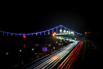 Fototapeta na wymiar Glowing pedestrian bridge in the night fog and the light of cars. Kyiv. Ukraine