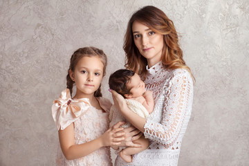 Mother and children newborn and older sister. Toddler sister hugging her newborn brother. Happy family with children at home. Love, trust and tenderness concept.