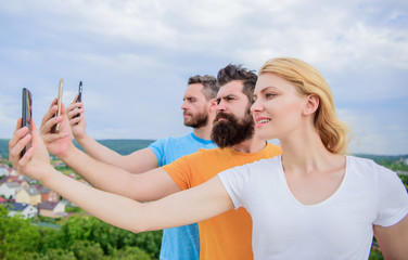 Experiencing digital picture sharing. Best friends taking selfie with camera phone. People shooting selfie on nature. Sexy woman and men holding smartphones in hands. Sharing selfie on social network