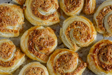 Homemade spirale cookies of puff pastry, cinnamon and nuts on gray baking tray, pan. Top view