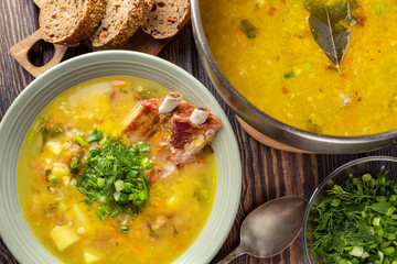 Delicious yellow split peas soup with smoked pork ribs  on a wooden table. Top view