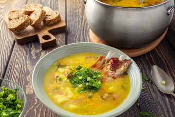 Fragrant yellow split pea soup  with smoked pork ribs  on a wooden table.