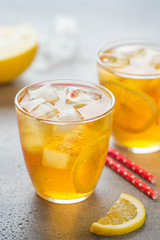 Cold tea with lemon and ice in a glass with drops, fresh sweet fruit drink, summer freshness, delicious lemonade