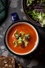 Orange vegetable cream soup in mug (tomato, carrot, lentil, pumpkin), delicious hot homemade lunch in cup. Dark background