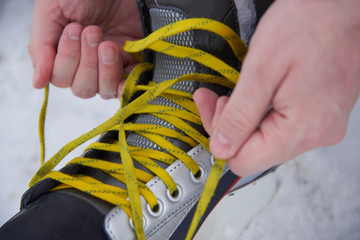 A man tying skates in the snow in winter