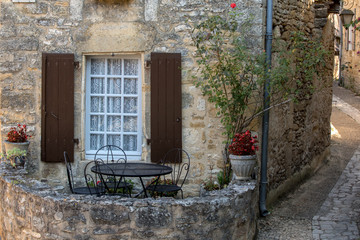 Fototapeta na wymiar A black metal table and chairs on the romantic terrace of an old stone house in Beynac-et-Cazenac, France