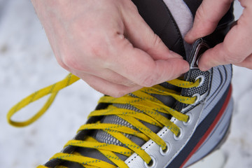A man tying skates in the snow in winter