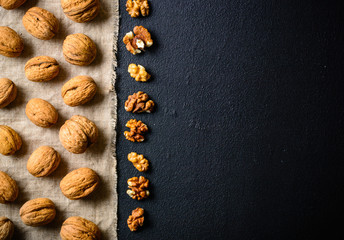 Walnuts on a black slate. Whole and peeled nuts. Walnuts spread out evenly.