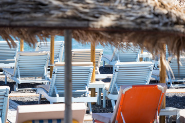 beach with umbrellas and deck chairs by the sea in Santorini