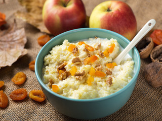Millet porridge with dried apricots and nuts on the background of autumn leaves